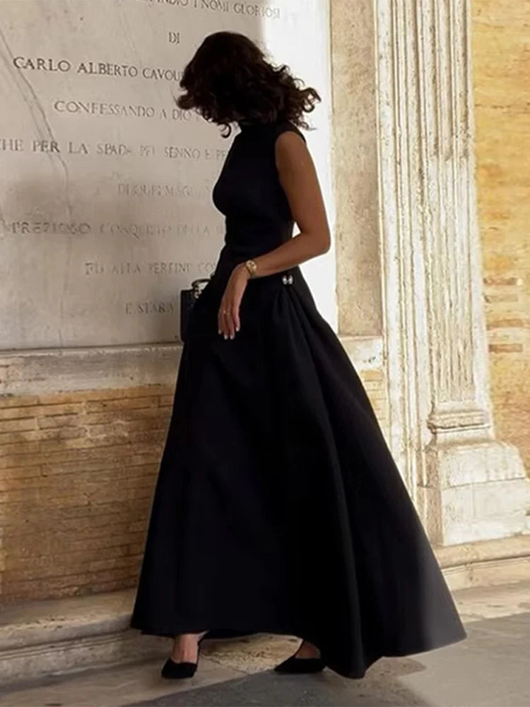 Woman in a black dress standing against a stone wall with inscriptions