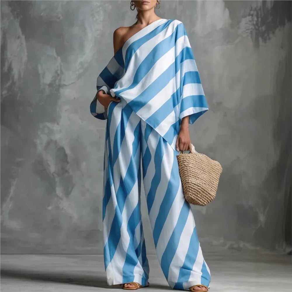 Woman wearing a blue and white striped dress holding a woven bag against a gray background