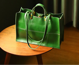 Green handbag on a wooden table with a dark curtain background