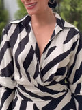 Person wearing a black and white patterned shirt with blurred background