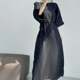 Person wearing a black dress with a geometric pattern in a minimal indoor setting