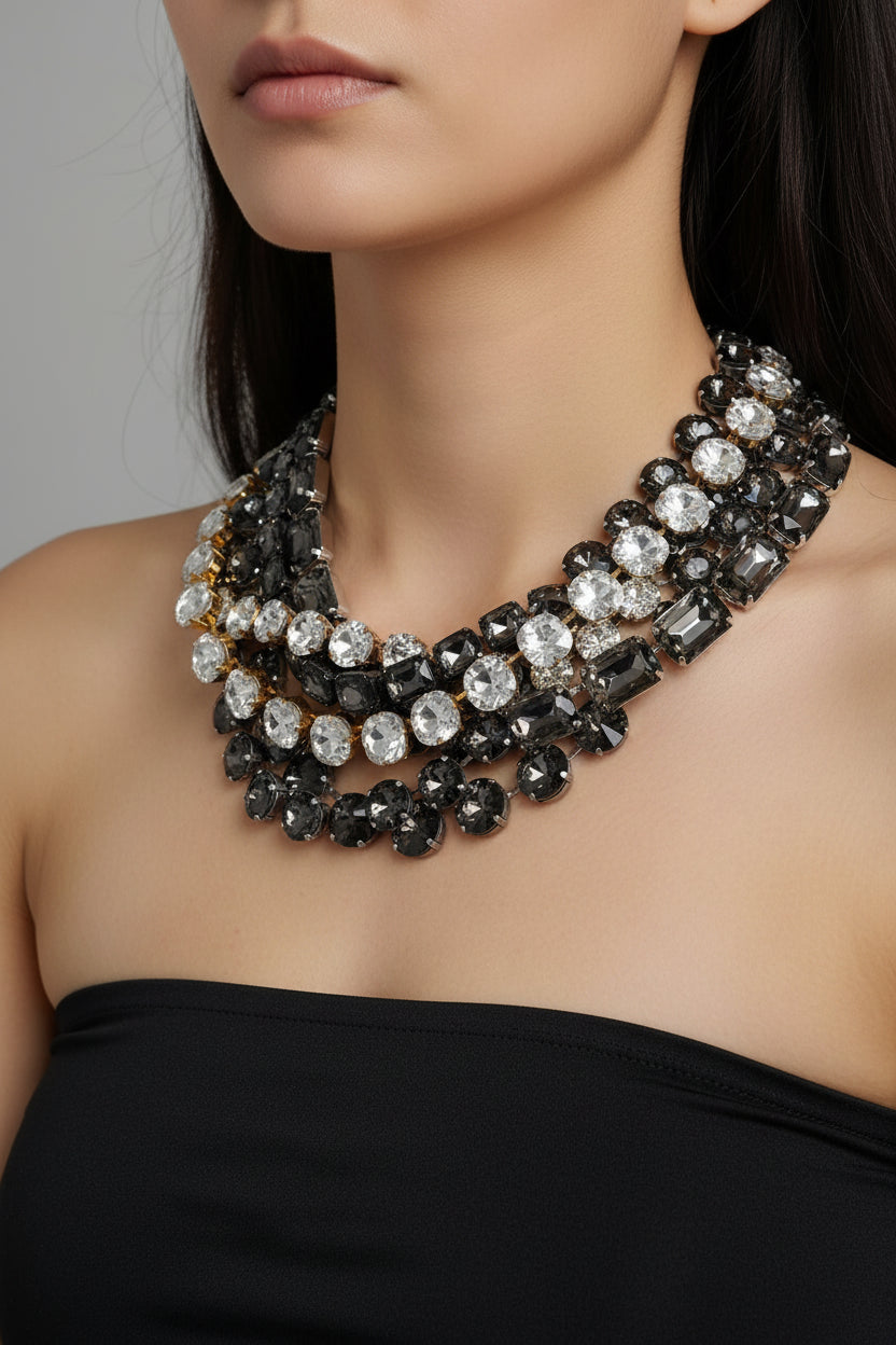 A multi-strand statement necklace featuring faceted black and clear rhinestones, displayed on a beige mannequin bust.