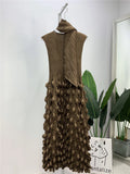 Brown textured dress hanging on a white wall with a plant in the background