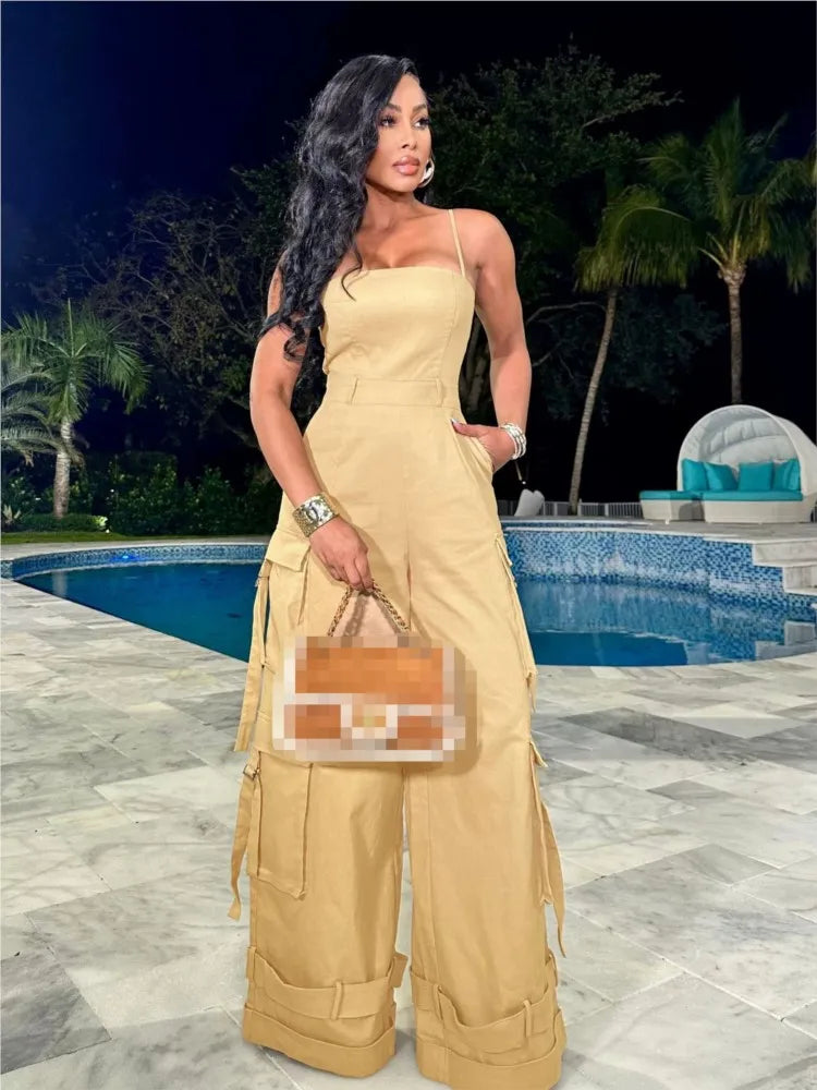 A woman modeling a beige sleeveless jumpsuit with multiple pockets, wide-leg pants, and a tube top style.