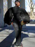 Person wearing a black outfit with large sleeves in an outdoor setting.