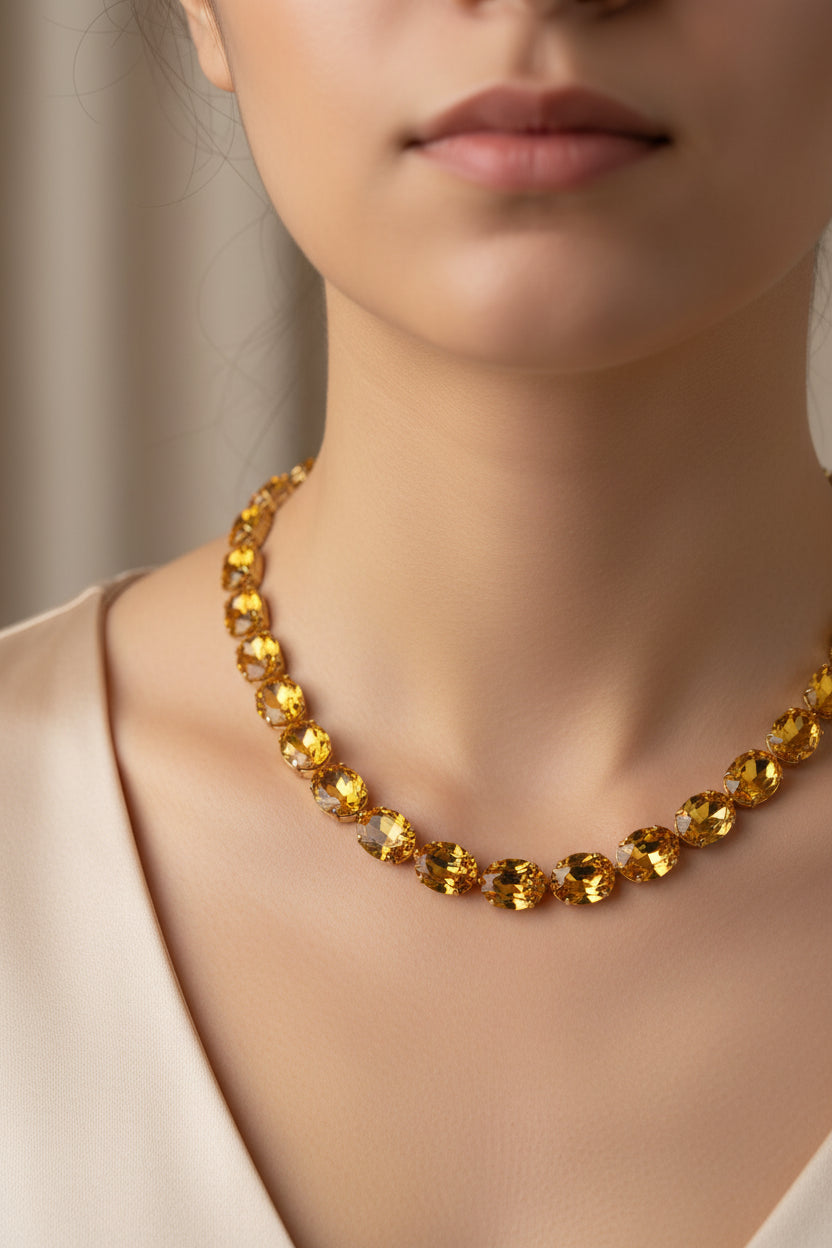 Gold necklace with amber-colored beads on a light gray background