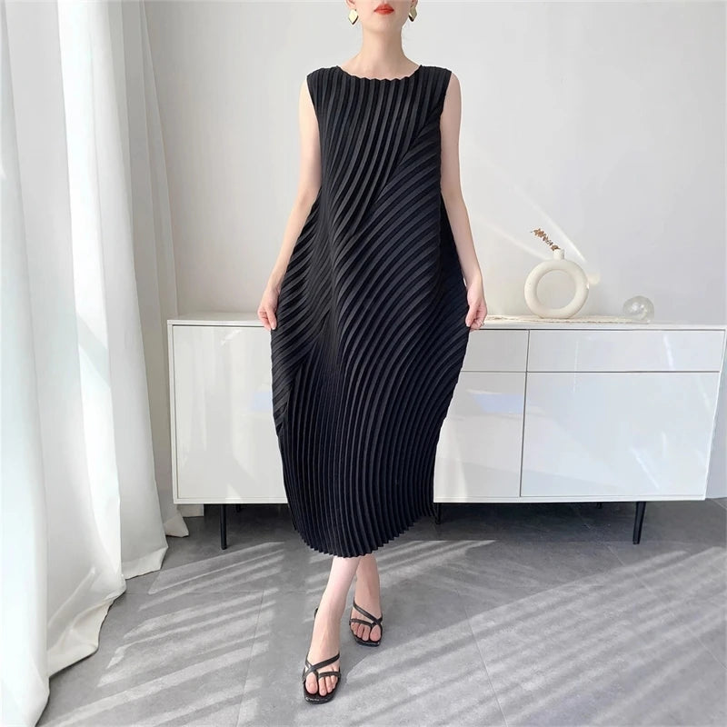 Woman wearing a black pleated dress in a minimalistic room.
