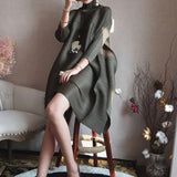 Person wearing a long dark green sweater in an indoor setting with decorative elements.