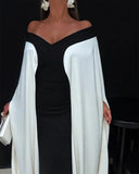 Woman wearing a black dress with white sleeves against a black background