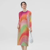 Woman wearing a colorful dress holding a white handbag on a light gray background