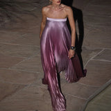 Woman wearing a strapless pleated dress on a stone pavement.