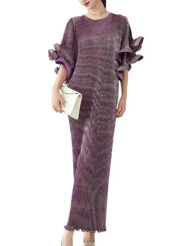 Woman wearing a long, patterned dress with ruffled sleeves on a white background
